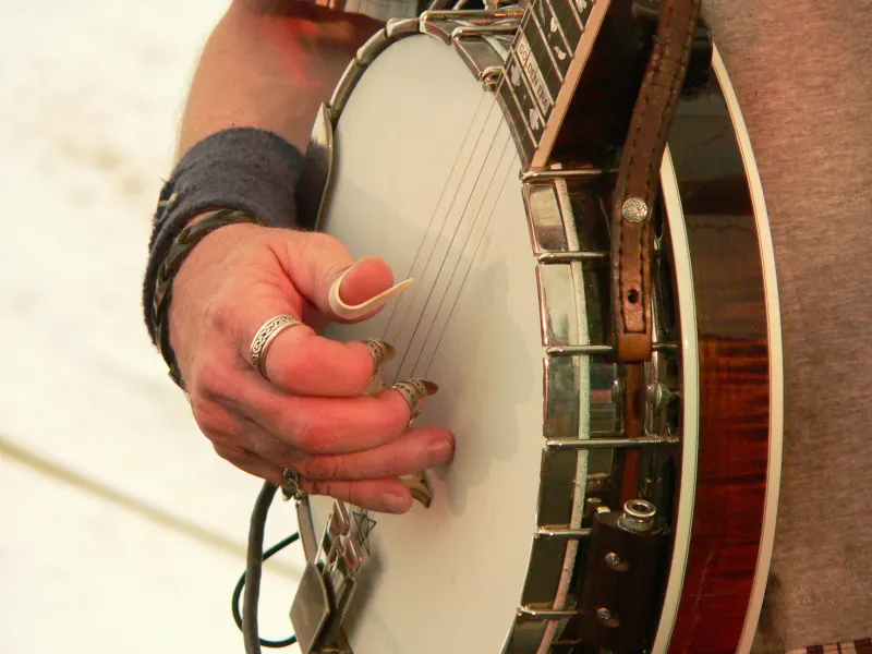 A bluegrass banjo being picked with fingerpicks