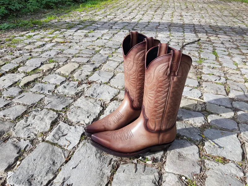 A pair of cowboy boots standing on cobblestones