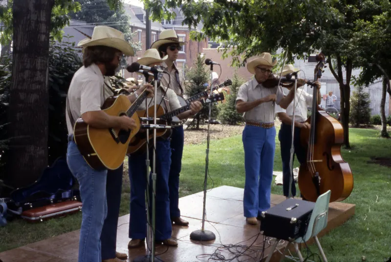 A string band with guitar, banjo, fiddle and bass playing outdoors